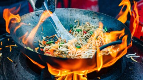 chef cooks Chinese noodle wok at street food festival