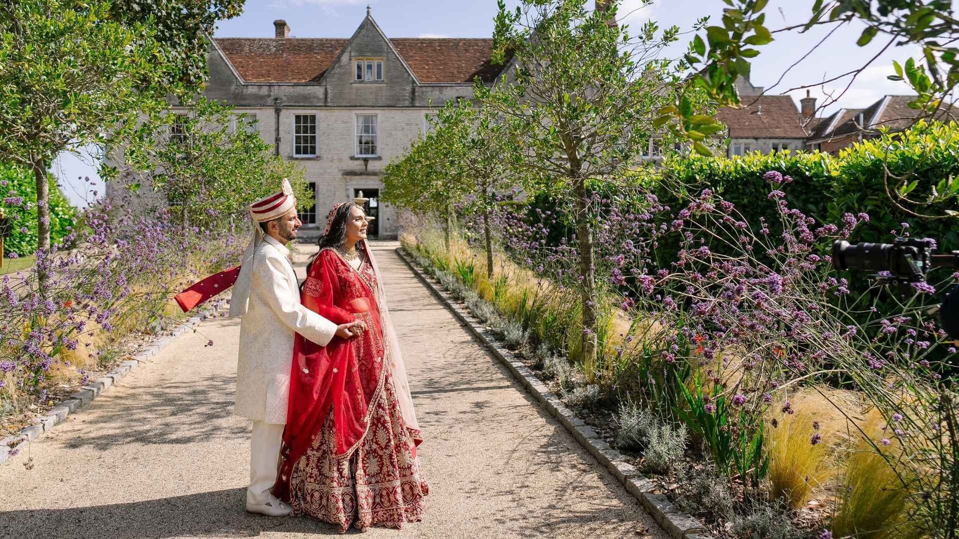 Hindu Bride & Groom posing at the front of Froyle Park's well manicured entrance