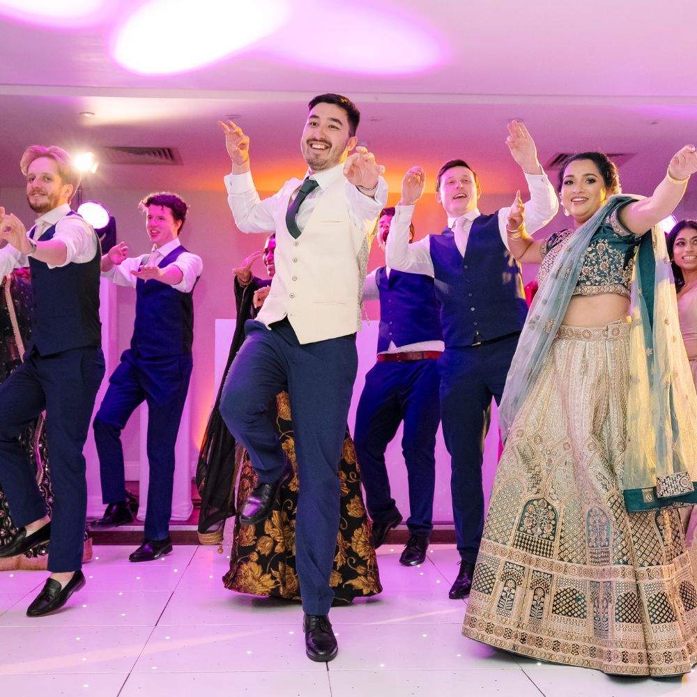 A Asian Bride & Groom do a cultural dance with members of their wedding party in Froyle Park's Grand Ballroom in Surrey
