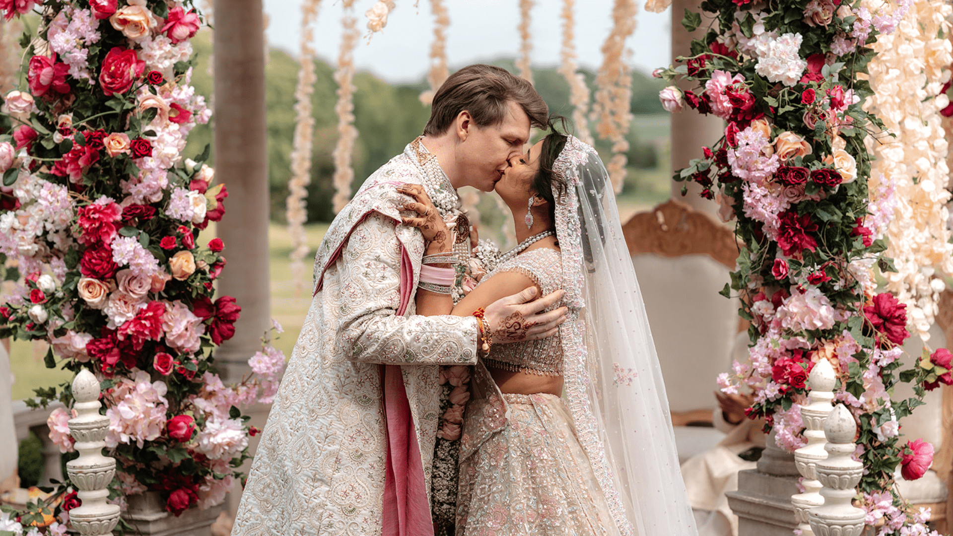 a couple seal their Hindu wedding ceremony with a kiss beneath the adorned outdoor mandap