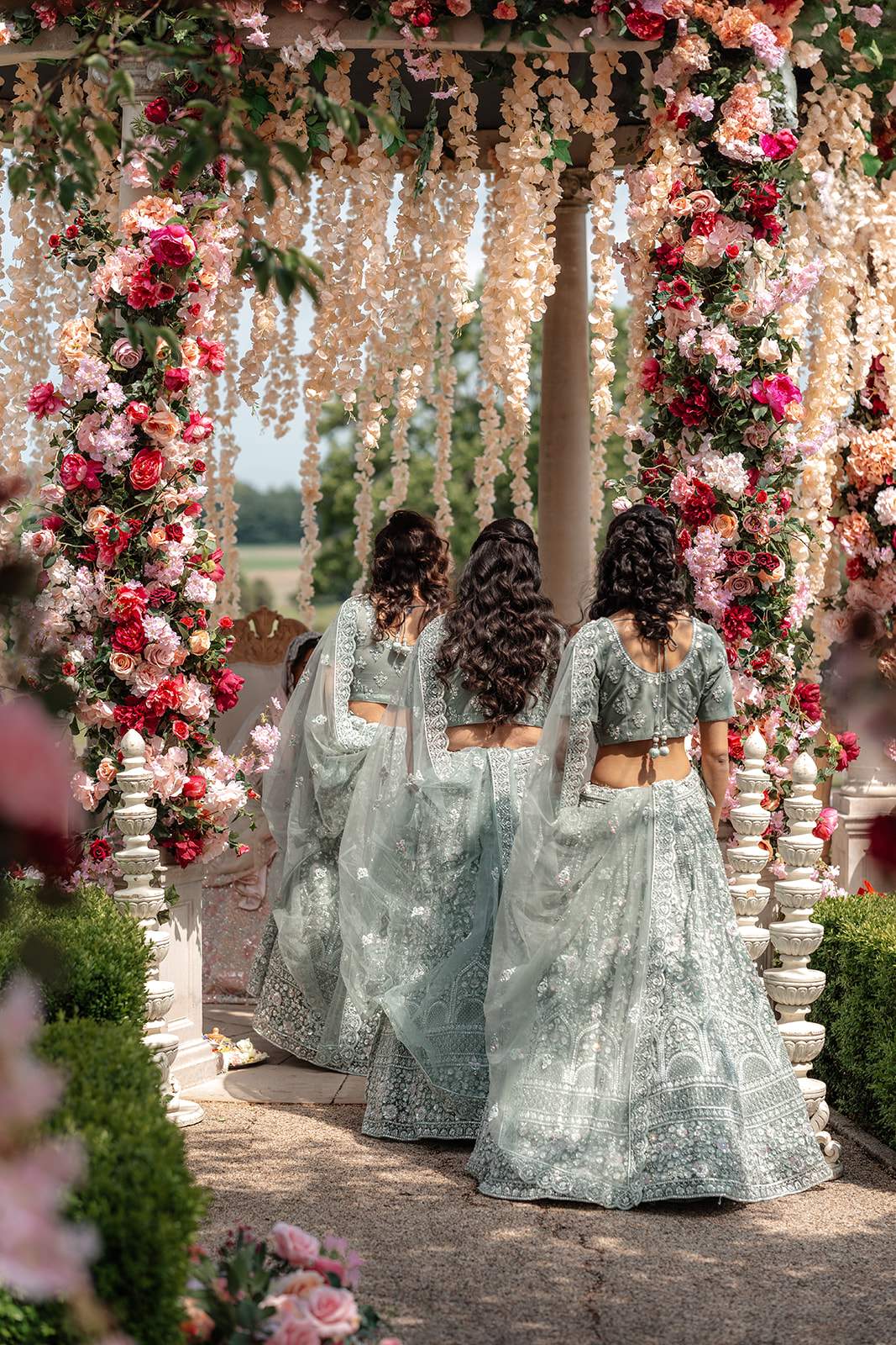 Bridesmaids in jewelled saris enter the outdoor mandap for the Hindu ceremony