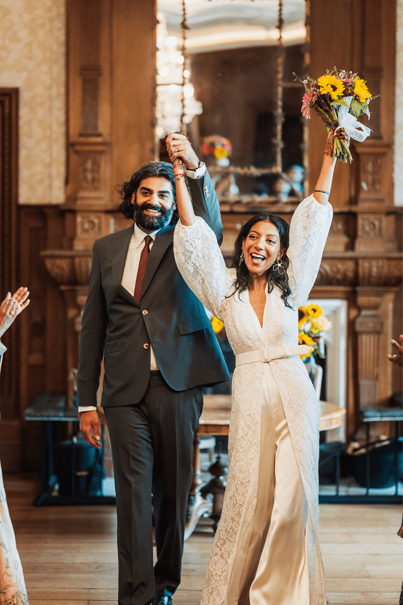 A bride and groom celebrate as the descend the aisle after their wedding ceremony in the Great Hall at Froyle park