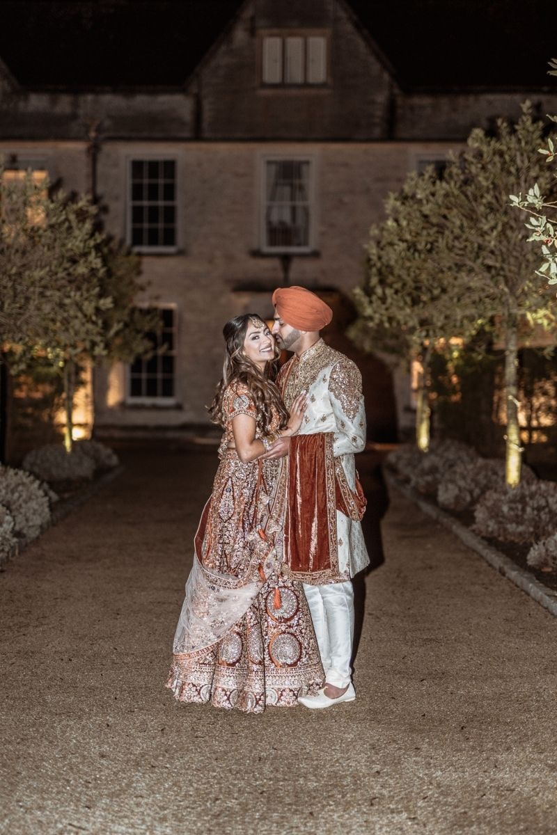 A Sikh bride and groom post in front of the manor house at Froyle Park
