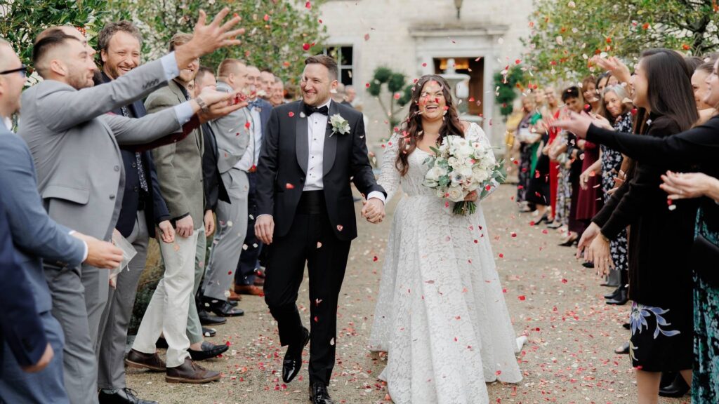 A Bride and Groom aer showered in confetti in front of the manor house at Froyle Park in Surrey