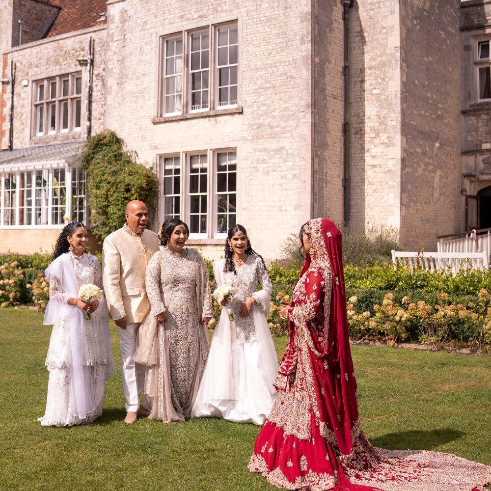An Asian bride reveals her copmpleted wedding look to her family at Froyle Park