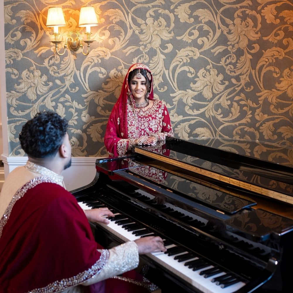 Asian bride and groom playing the piano at Froyle Park