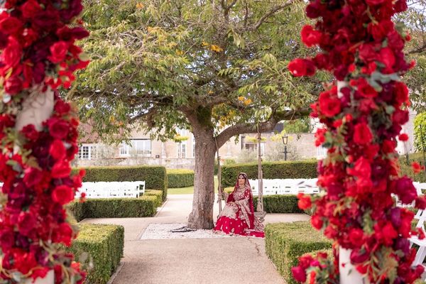 An Sian bride sits on the swing in the Froyle Park gardens