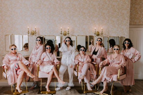 A Bride & her bridesmaids pose for photos whilst getting ready in Froyle Park's Bridal Hideaway.